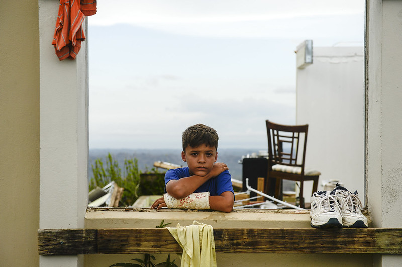 Young boy in front of hurricane-damaged house in Puerto Rico
