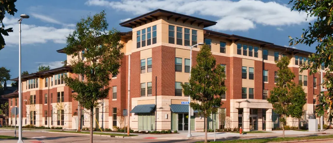 Brick multifamily building viewed from corner against a blue sky