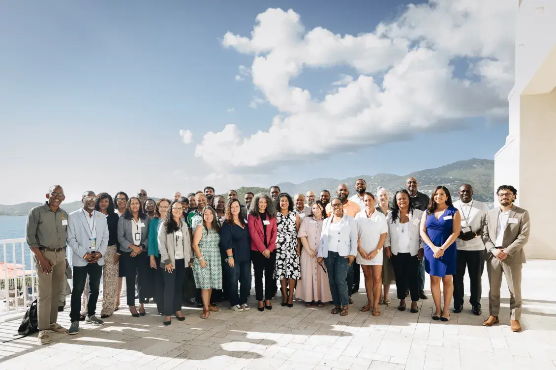 Enterprise U.S. Caribbean team and U.S. Virgin Islands Housing Ecosystem Development Grant Program grantees outside with the ocean and hillside in the background