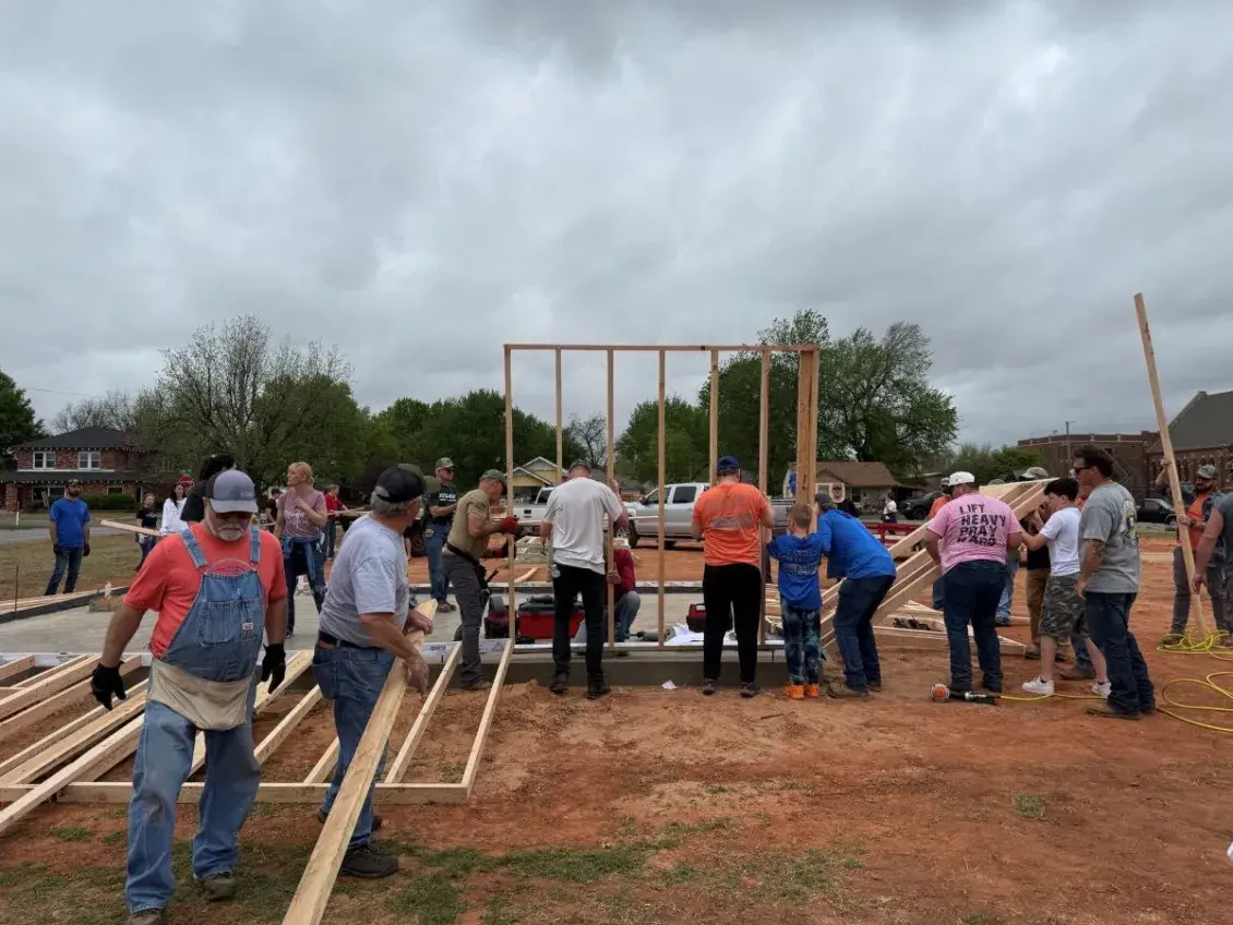 People in work clothing raising a wooden frame up together