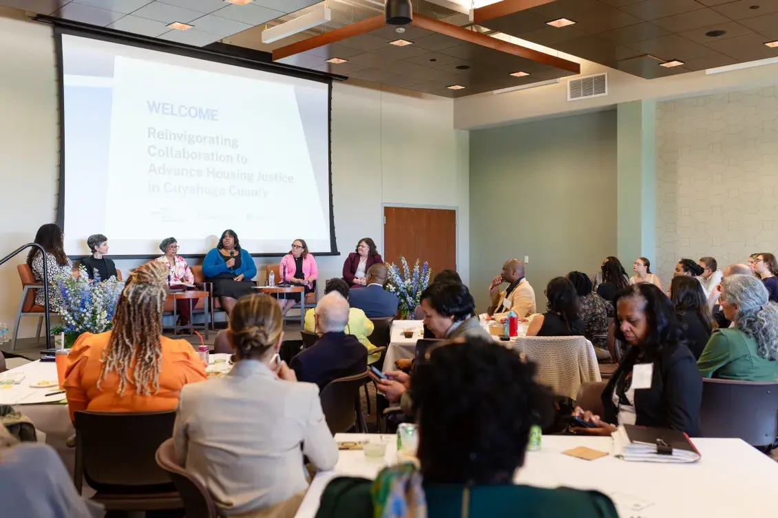 140 partners gather in a room and listen to a panel discussion. 