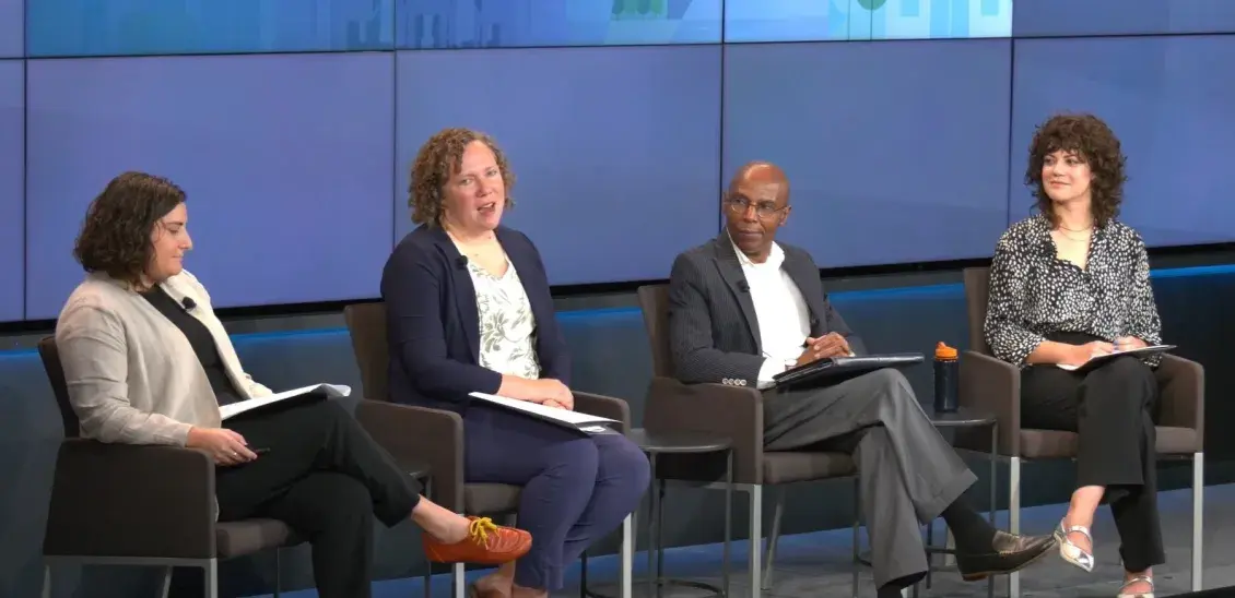 Four people sit on chairs on stage in conversation