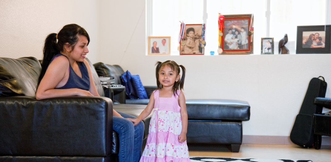 lady sitting on a sofa looking at a little girl standing in front of her