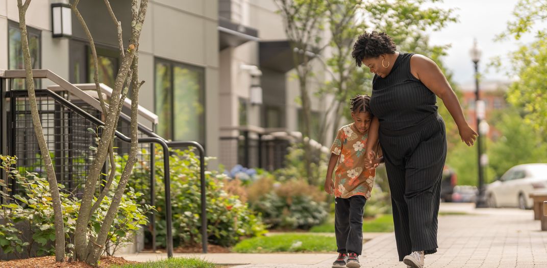 A mother and her son walking down the street smiling