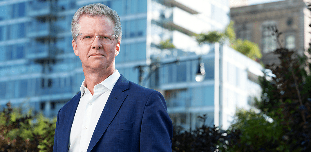 Shaun Donovan, CEO and President of Enterprise Community Partners, stands outside with buildings in the background