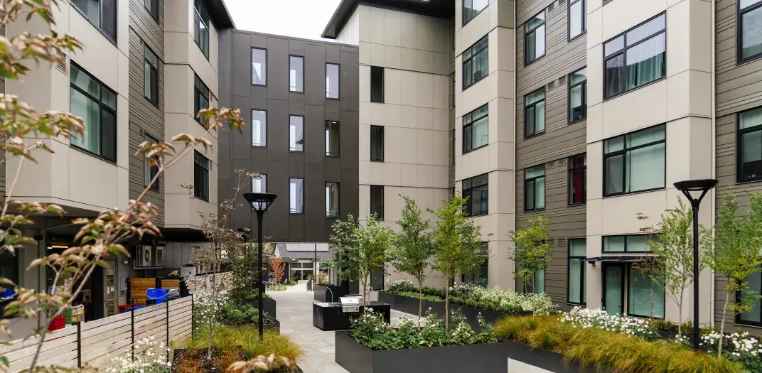 An apartment building courtyard with tree boxes and lamp posts