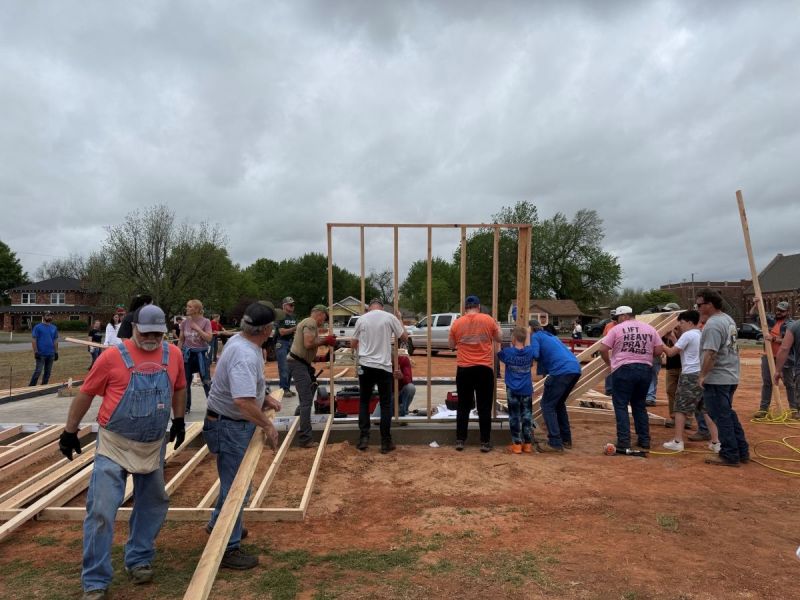 People in work clothing raising a wooden frame up together