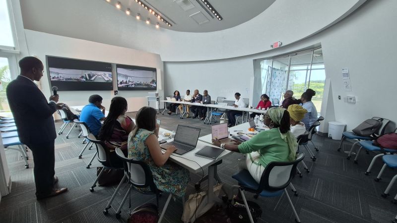 Attendees at the USVI Affordable Housing Workshop in a conference room with two screen projections