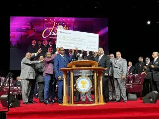 Group on a stage hold an oversized check