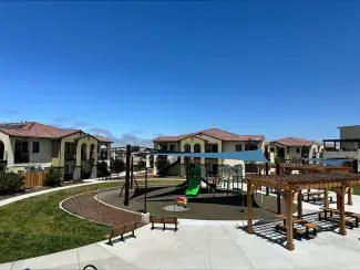 Apartments at Escalante Meadows with a playground and sitting area in the foreground 