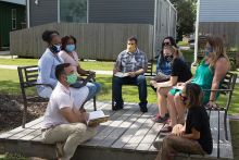 People sitting around outside with mask on.