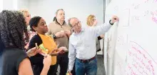 group of people in discussion at a white board