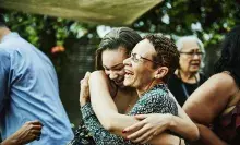 two ladies hugging at a social event