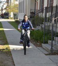 boy riding his bike down a sidewalk