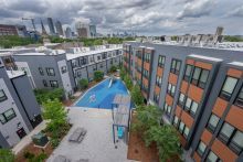 Rooftop view of multifamily housing development showing a courtyard, playground, and a blue sky and white puffy clouds overhead 