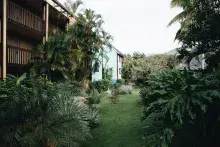 Two story apartment building in development with palm trees and other foliage