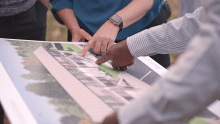 The hands of two people pointing at a picture.