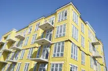 Aspect of a multistory building with yellow insulation and a bright blue sky overhead.