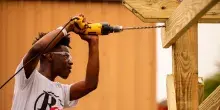 A person drilling a hole through wood