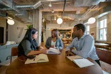Three people sitting around a table having a meeting