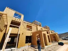 A worker stands in front of a building under construction