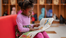 Young girl in pink shirt reading a picture book.