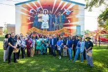 A group of individuals posing for a photo in front of a mural