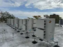 A row of rooftop heat pumps with a blue sky in the background