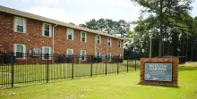Red-brick apartment building, black fence and green lawn