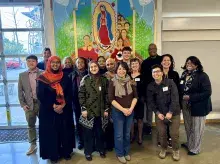 Group of smiling people standing in front of colorful mural