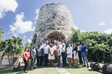Attendees at the Housing Our Community Workshop in St. Croix, USVI stand in front of a historic structure with trees beside it