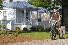 Young boy right biking pass colorful homes