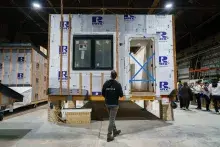 Person stands in front of modular housing in factory setting