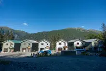 Row of six new singe-family homes with trees, mountains and blue sky in the background