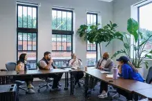 Five people sitting around tables having a discussion