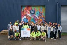 A group of people standing in front of a colorful wall mural