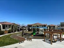 Apartments at Escalante Meadows with a playground and sitting area in the foreground 
