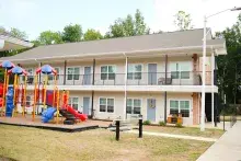 Two story brick and beige siding apartment building with playground in front