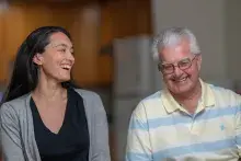 Two people sit side by side smiling and laughing.