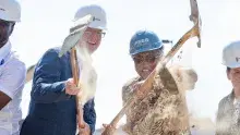 Shaun Donovan, CEO of Enterprise Community Partners, and other people dig and throw dirt with shovels at a groundbreaking ceremony