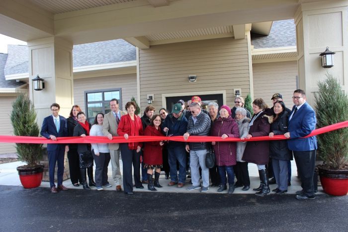 A group of people cutting a ribbon for a grand opening.