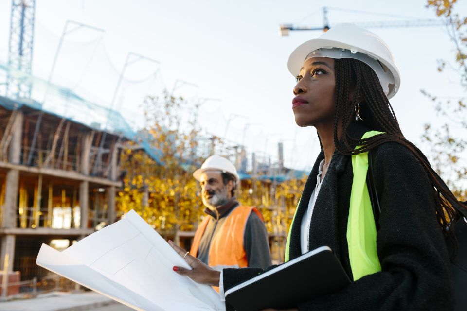 Black woman holding construction plans at a construction site during build