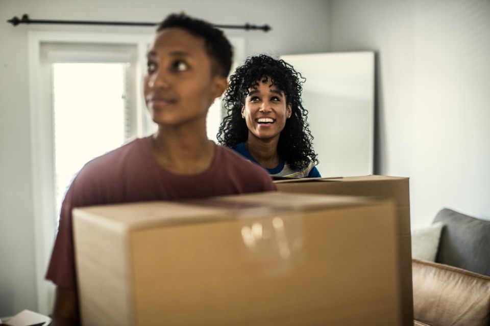 two people moving boxes in a residence