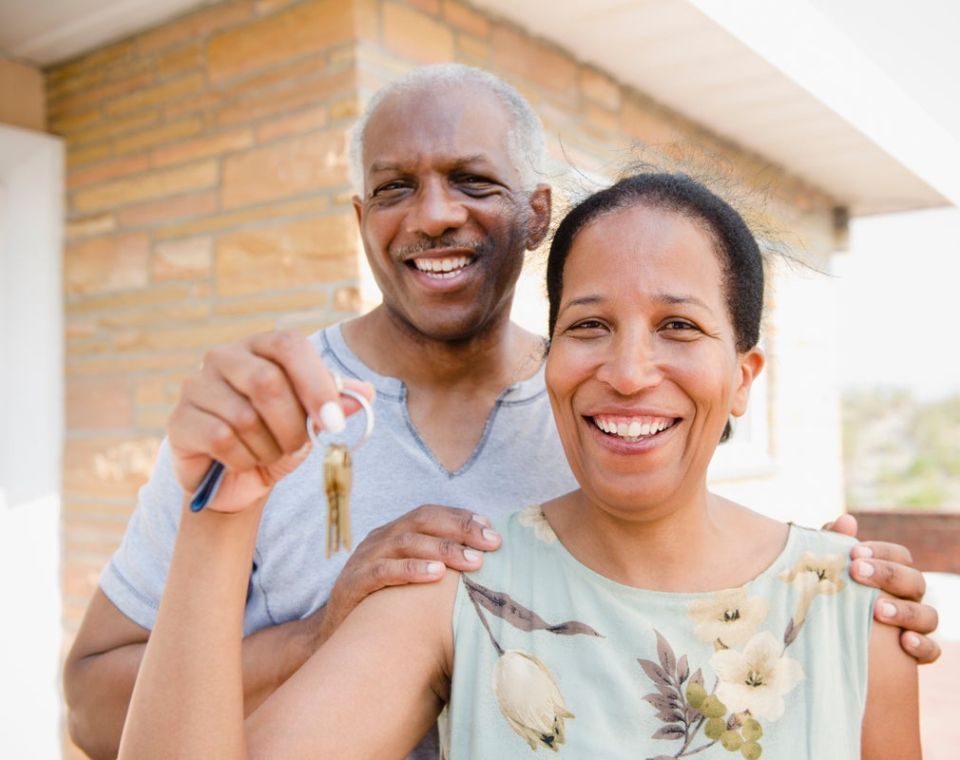 a man and woman holding keys in front of a house
