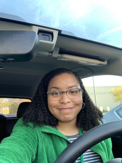 Selfie of woman wearing green blouse inside of a car