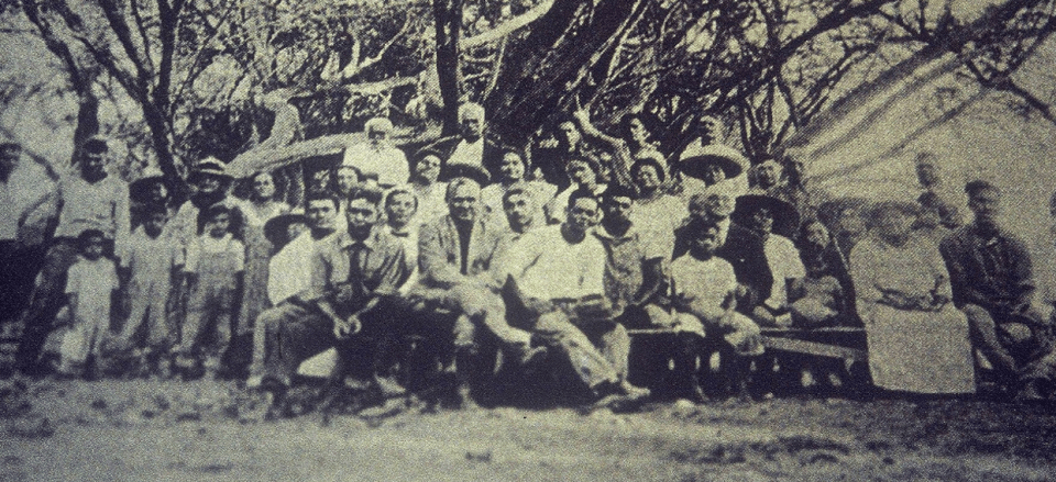 An older photo showing a large group of people seated and facing the camera