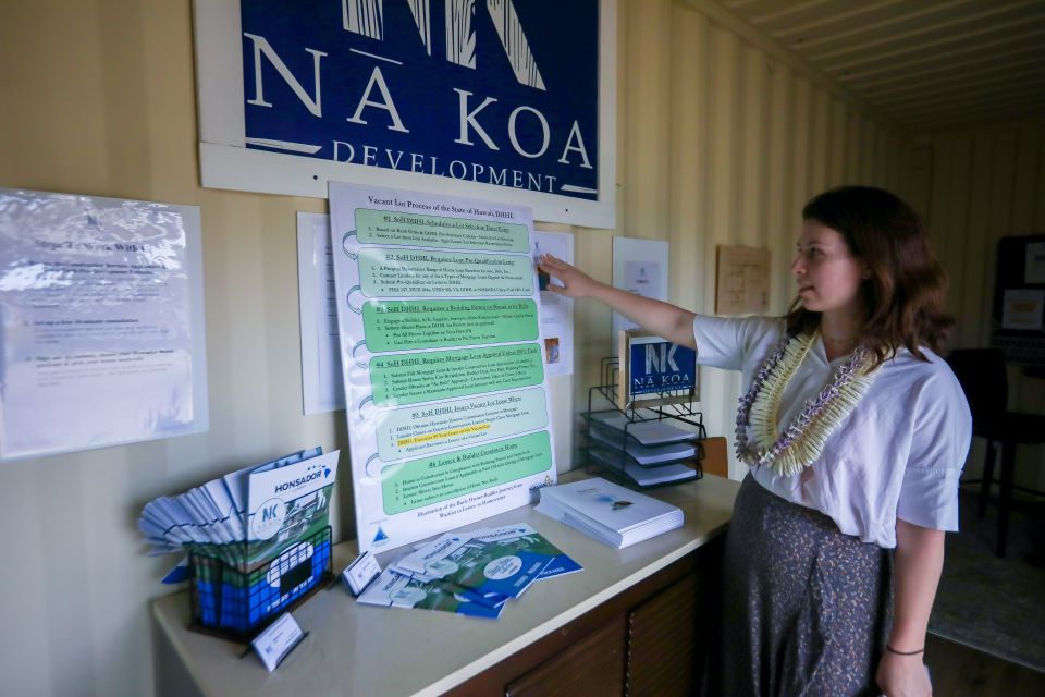A person stands in front of a poster board and points