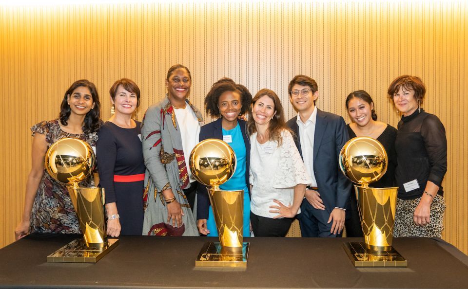 Group of People Standing Behind Championship Basketball Trophies