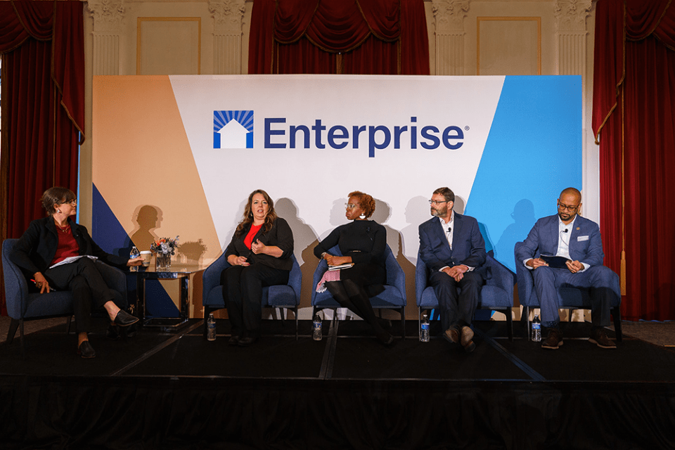 Five panelists, sitting on a stage, speak during the Preserving Affordable Homes session