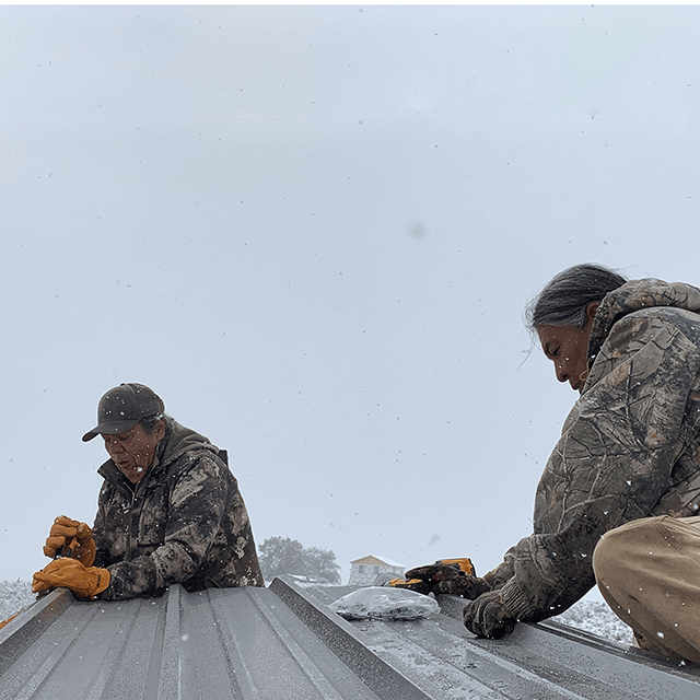Two men working on the roof of a building